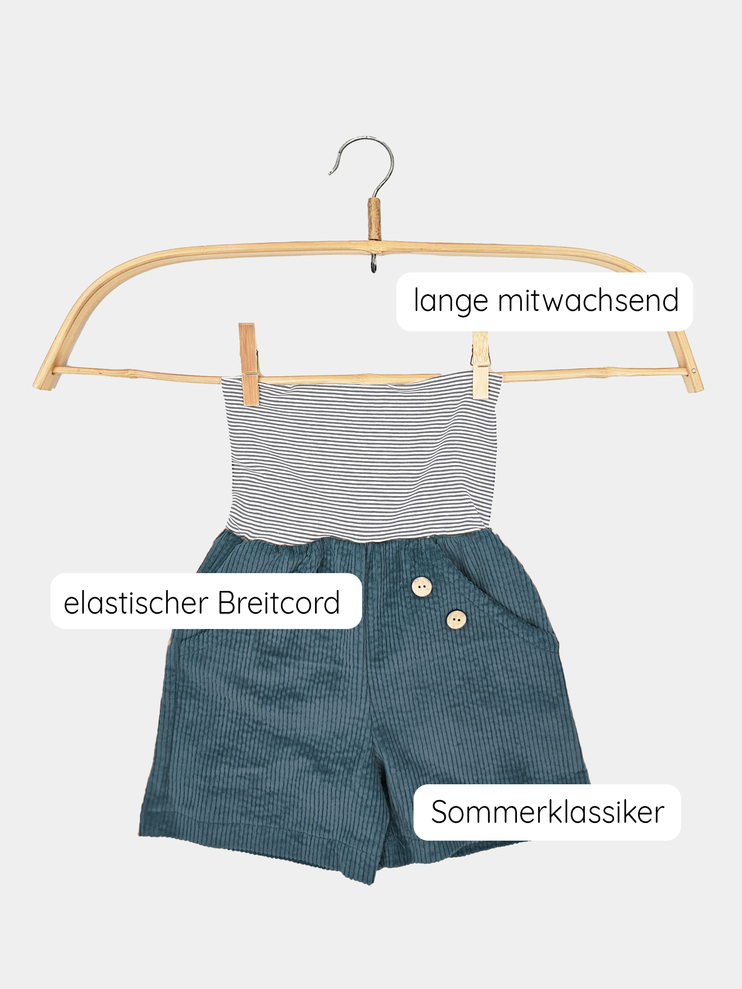 Kurze Buxe Breitcord Denim auf Kleiderbügel, gestreiftes Bündchen sichtbar. Mitwachsende, nachhaltige Shorts aus robustem Bubblecord, bequem und in Berlin gefertigt.