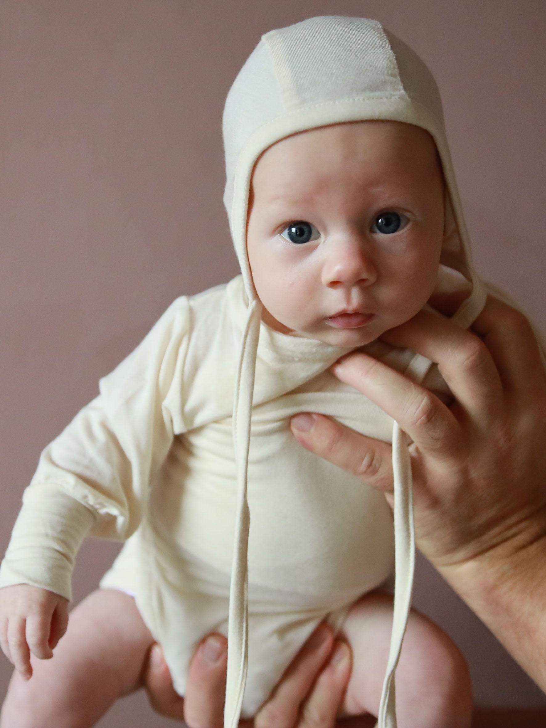 Ein Baby trägt den Loopbody Seide-Viskose ohne Knöpfe, der den Bauch umhüllt und atmungsaktiv sowie weich ist.